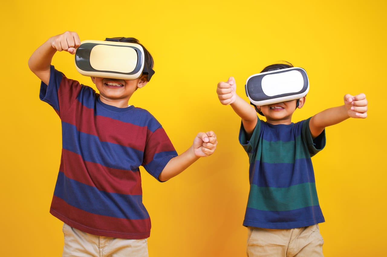 Two boys in VR headsets with their arms raised, cheering.
