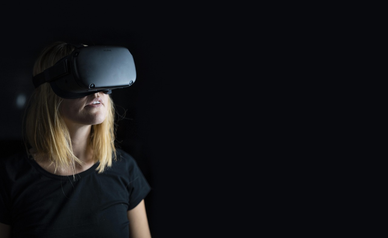 A woman wearing a VR headset in a dark room.